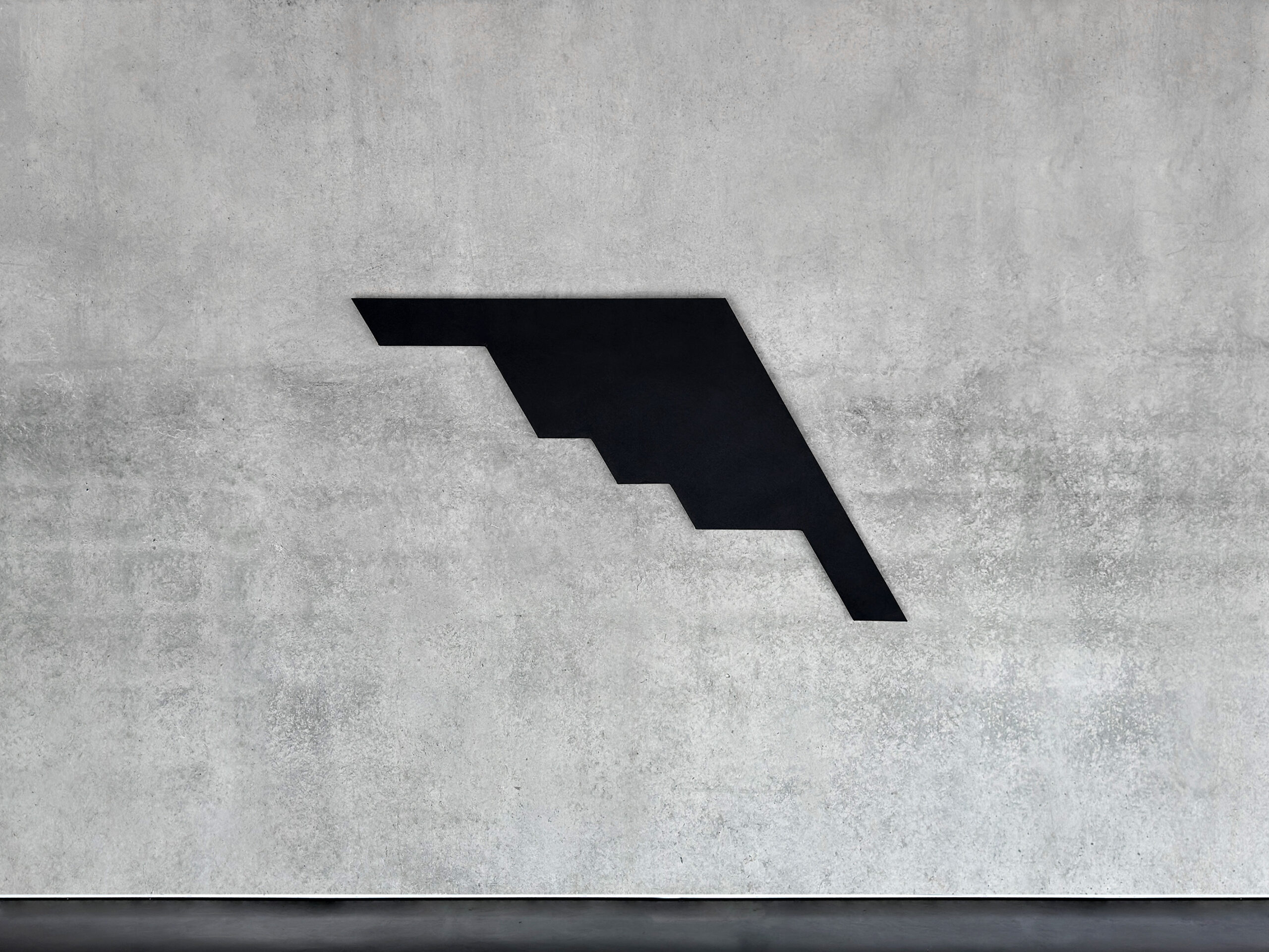 Black monochrome shaped canvas B2A1 by Jean-Charles Kien mounted horizontally on a raw concrete wall