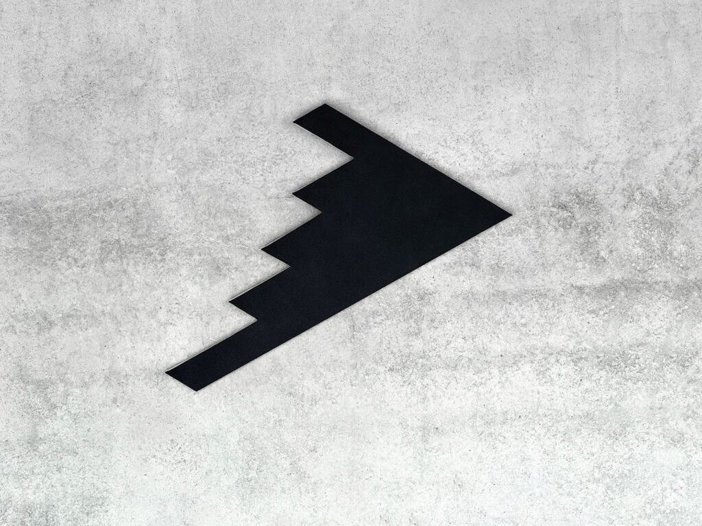 Black monochrome shaped canvas B2S2 by Jean-Charles Kien mounted on a raw concrete wall