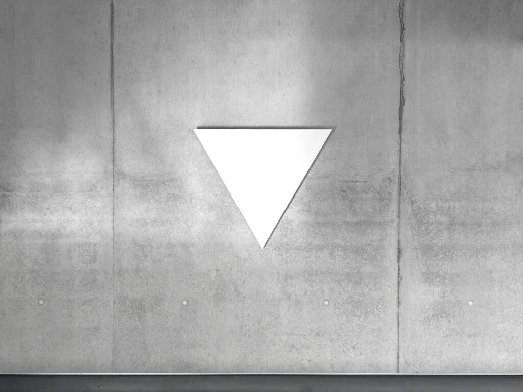 White monochrome shaped canvas painting WTM1 by Jean-Charles Kien, featuring an inverted triangle on a concrete wall