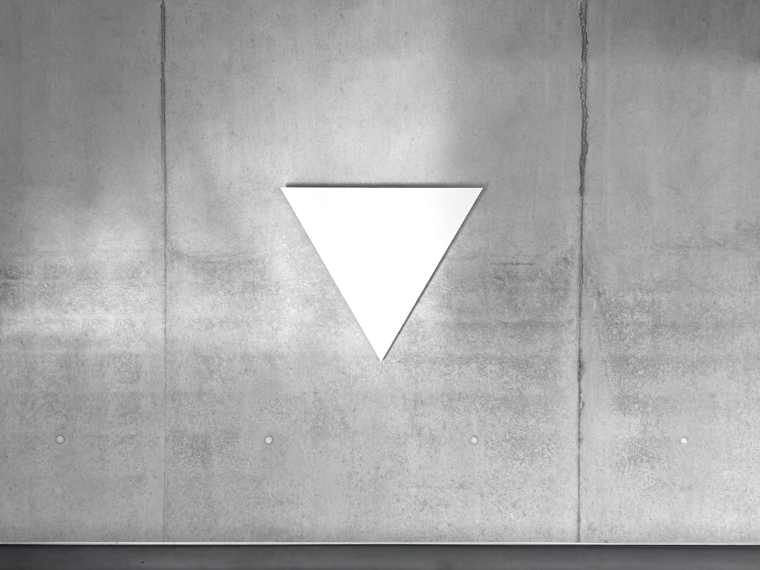 White monochrome shaped canvas painting WTM1 by Jean-Charles Kien, featuring an inverted triangle on a concrete wall