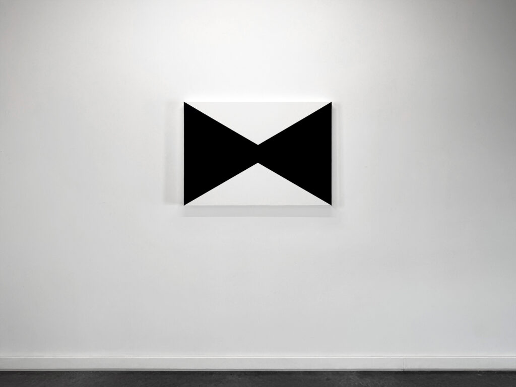 Front view installation shot of a minimalist horizontal rectangular painting by Jean-Charles Kien featuring two opposing black triangular fields meeting at the center.