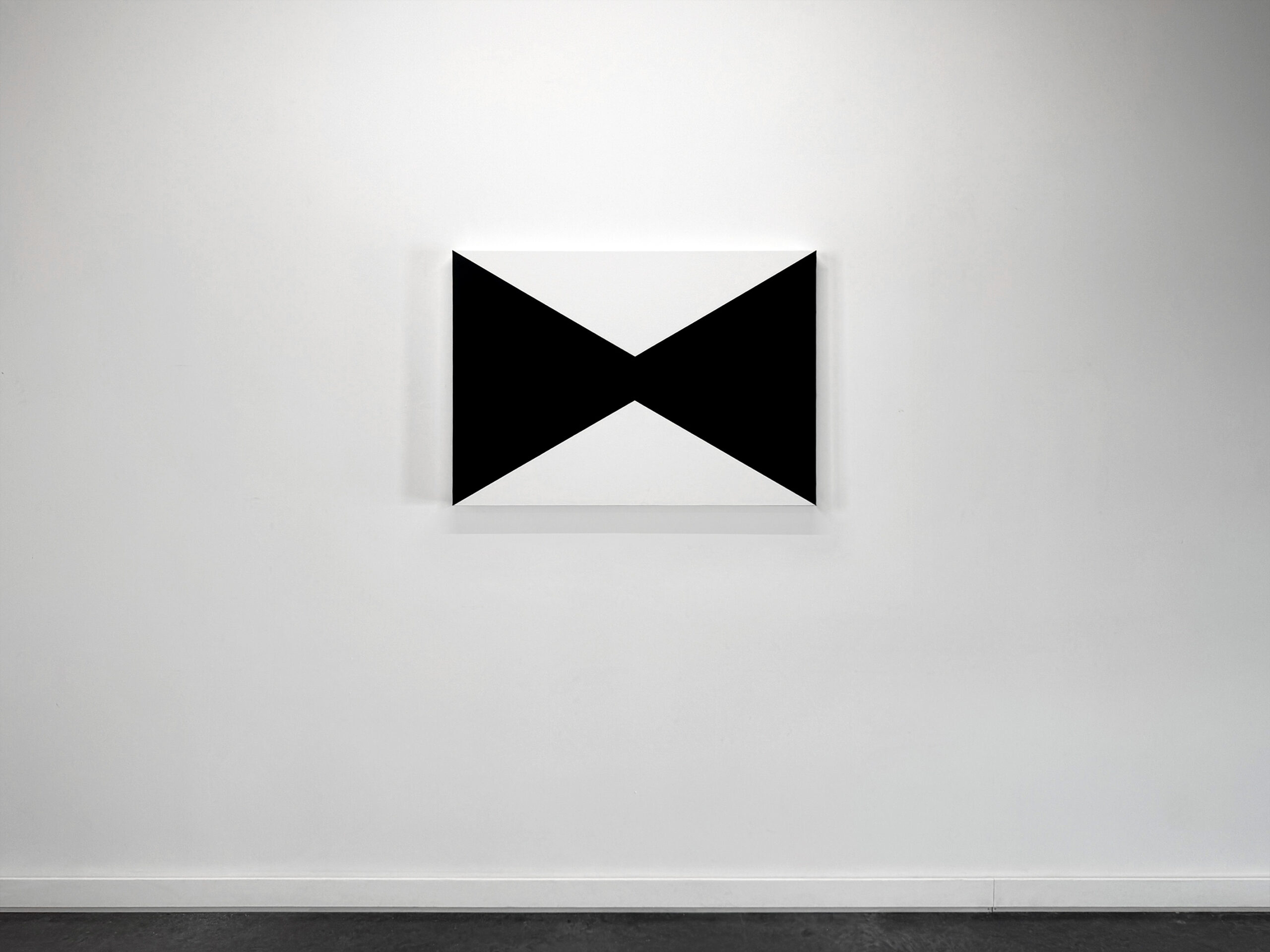 Front view installation shot of a minimalist horizontal rectangular painting by Jean-Charles Kien featuring two opposing black triangular fields meeting at the center.