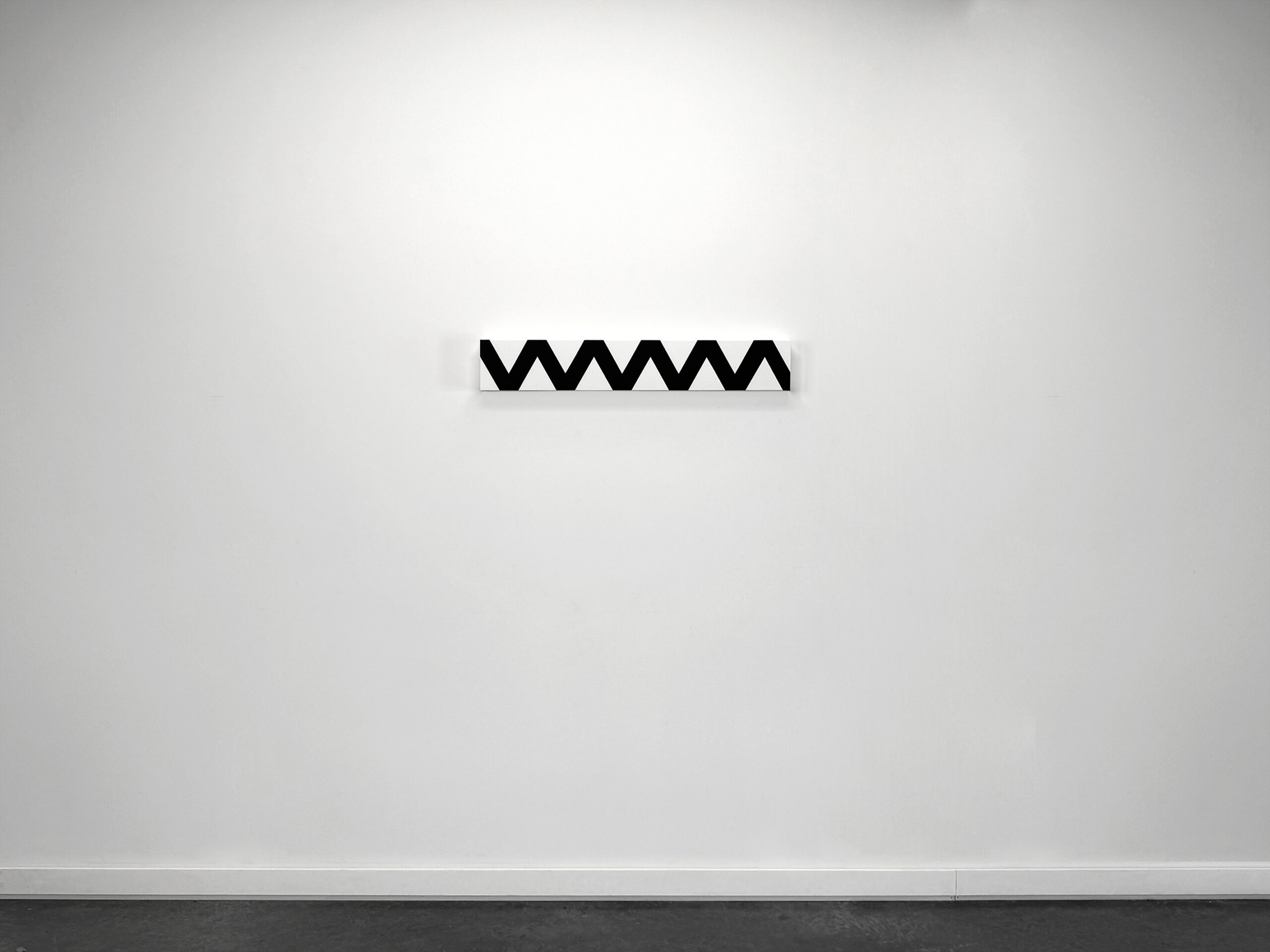 Wide installation shot of a minimalist horizontal painting by Jean-Charles Kien featuring a black wavy zigzag pattern on a white canvas, mounted centrally on a stark white gallery wall.